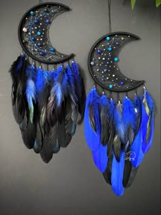 two black and blue feathers hanging from the side of a moon shaped wall hooks