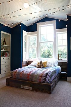 a bedroom with blue walls and lights strung from the ceiling