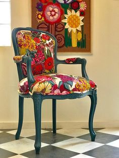 a colorful chair sitting on top of a checkered floor in front of a painting