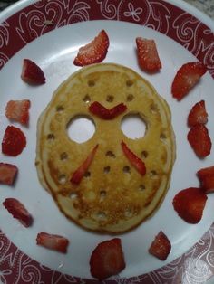 a pancake with strawberries on it and a face made out of the pancakes