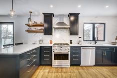 a kitchen with wood floors and white counter tops, black cabinets and stainless steel appliances