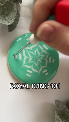 a person is painting a green object with white paint on it and the words royal icing 101 are in front of them