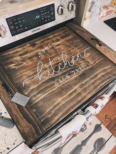 a wooden sign that says kitchen on it next to a stove top with utensils