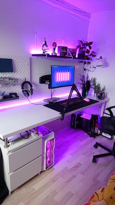 a computer desk with headphones on it and a purple light in the room behind it