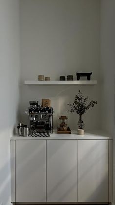 a kitchen with white cabinets and shelves filled with pots and pans on top of them