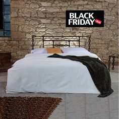 a black friday sign above a bed in a stone walled room with white sheets and pillows