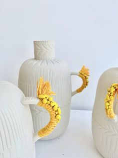 three white vases with yellow decorations on them