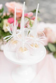 three candy lollipops sitting on top of a cake plate with flowers in the background