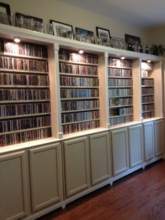 a room filled with lots of books on top of white shelves next to a hard wood floor