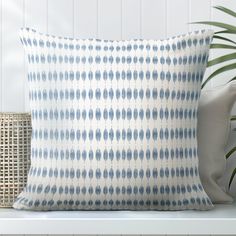 a blue and white pillow sitting on top of a wooden bench next to a potted plant