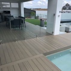 an outdoor deck with chairs and table next to the water