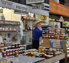 an older man standing in front of a store filled with honey jars and jams