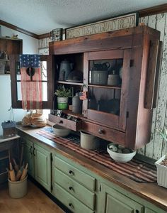 an old fashioned kitchen with green cabinets and wood flooring on the counter top, along with pots and pans