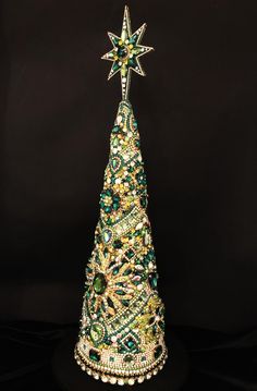 a christmas tree made out of beads on a black surface with a star in the middle