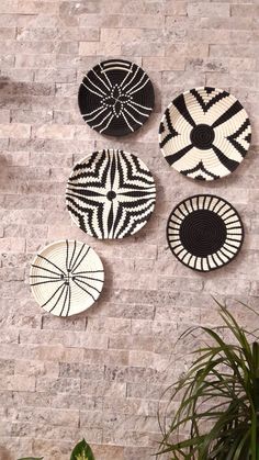 four black and white baskets hanging on a brick wall next to a potted plant