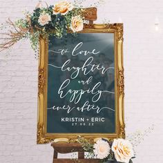 a wedding sign with flowers and greenery in front of a white brick wall that reads, to love laughter and happily ever