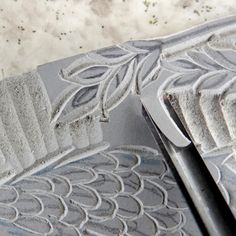 an intricately designed metal object on a marble counter top, with the edge partially covered in frosting