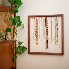 a wooden frame holding several necklaces and a potted plant