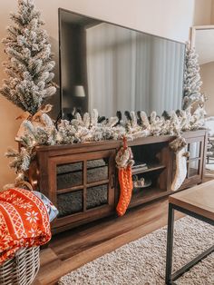 a living room with a christmas tree and stockings on the tv stand in front of it