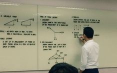 a man standing in front of a whiteboard with diagrams on it and writing on the board