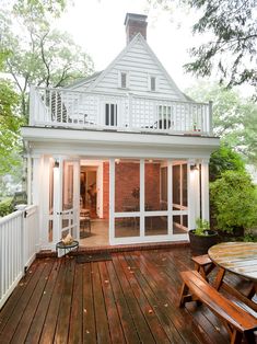 the back deck has two wooden benches on it and is next to a white house