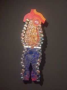 a piece of art made out of glass and beads on a black surface with a person standing in the middle