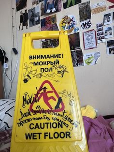 a yellow caution sign sitting on top of a bed next to a wall covered in pictures