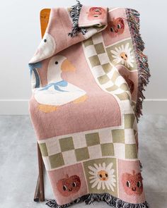 a pink blanket with an animal design on it and fringe trimming around the edges