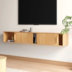 a flat screen tv mounted to the side of a wooden entertainment center next to a potted plant