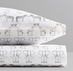 two sheets with giraffes and zebras on them, one is white