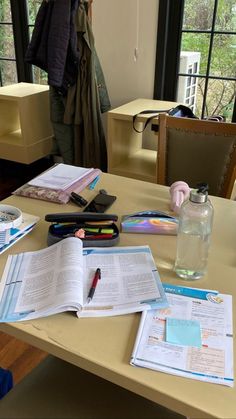 a table with books and papers on it in front of a woman looking out the window