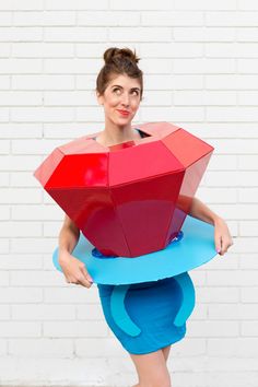 a woman in blue and red dress holding an umbrella shaped like a heart on top of her head