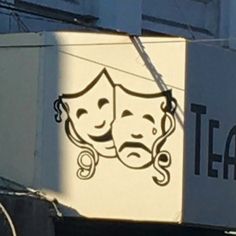 a building with a sign that says tea on it and two faces drawn on the side