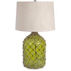 a green glass table lamp with a white shade on the side and a beige linen lampshade