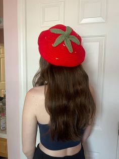 a woman with long hair wearing a strawberries hat in front of a white door