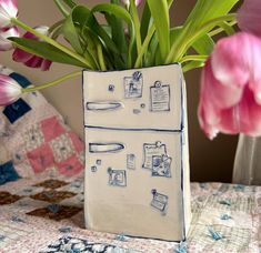 a vase with flowers in it sitting on a table next to a quilted pillow