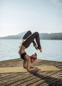 a woman doing yoga on a dock by the water