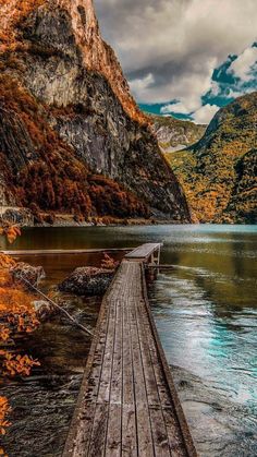 a wooden dock sitting on top of a lake surrounded by mountains