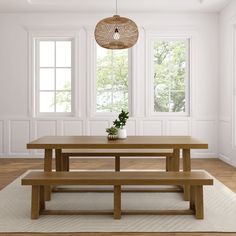 a wooden table and bench in a room with white walls, hardwood floors and windows