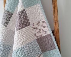 a blue and white quilt hanging from a wooden chair in front of a wall mounted clock