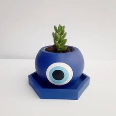 a blue planter with an evil eye on it's side and a succulent in the middle