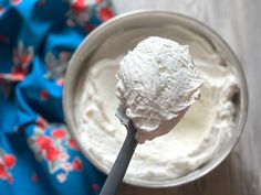 a spoon full of whipped cream sitting on top of a wooden table next to a blue cloth