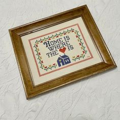 a framed cross - stitch pattern with the words home is where the heart is on it