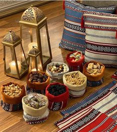 several bowls filled with nuts and raisins on a wooden floor next to a lantern