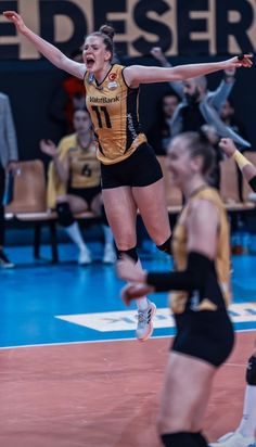 a volleyball player jumping in the air with his arms wide open and hands outstretched, while other players look on