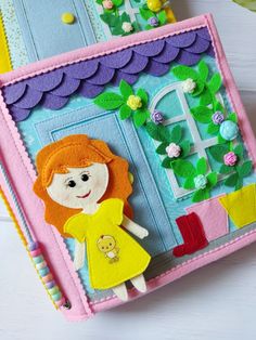 a close up of a crafting book with a doll on the cover and flowers in the background