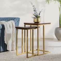 two side tables sitting next to each other on top of a carpeted floor in front of a blue couch