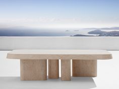 a white bench sitting on top of a cement slab next to the ocean and mountains