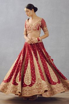 Bright red gota embroidered lehenga with scallop border and floral motifs in raw silk. Paired with gota embroidered blouse and golden thread embroidered sheer dupatta finished with fringes.
Component: 3
Pattern: Embroidered
Type Of Work: Dori, Adda
Neckline: Leaf
Sleeve Type: Half
Fabric: Lehenga and Blouse: Raw Silk, Dupatta: Butterfly Net
Color: Red
Other Details: 
Sheer dupatta
Tassel detail
Gota work blouse
Occasion: Bride,Wedding - Aza Fashions Red Embroidered Sets For Navratri, Red Sets With Intricate Embroidery For Navratri, Red Semi-stitched Kundan Sets, Red Gown With Dori Work For Traditional Ceremonies, Traditional Red Gown With Cutdana Details, Red Bollywood Lehenga With Cutdana, Red Choli For Navratri With Kundan Style, Red Zari Work Lehenga For Navratri, Red Lehenga With Zari Work For Navratri