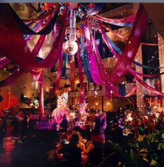 a large room filled with lots of decorations and people sitting at tables under the chandelier